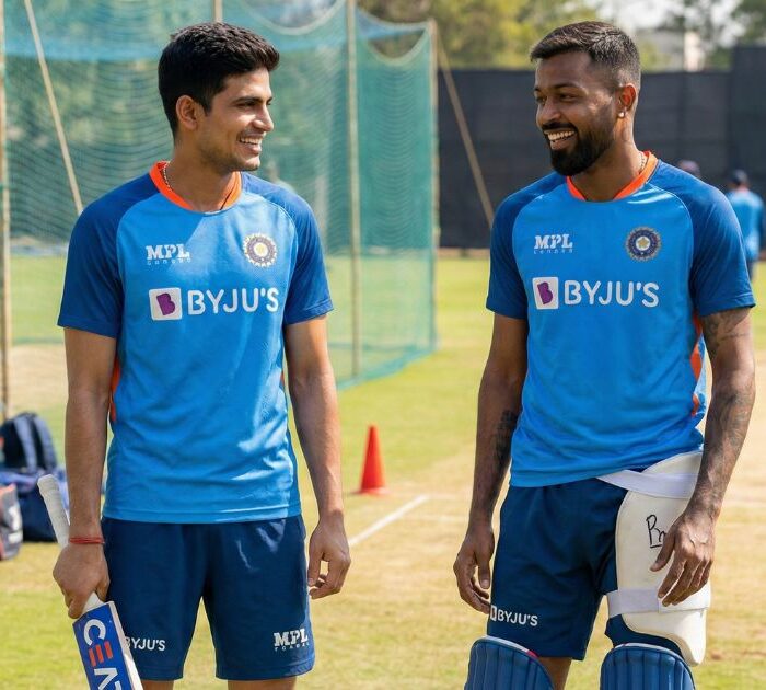 Indian cricket players Shubman Gill and Hardik Pandya in Team India blue jerseys at training ground, smiling confidently, cricket equipment visible, outdoor practice facility setting, bright natural lighting showing their return to fitness